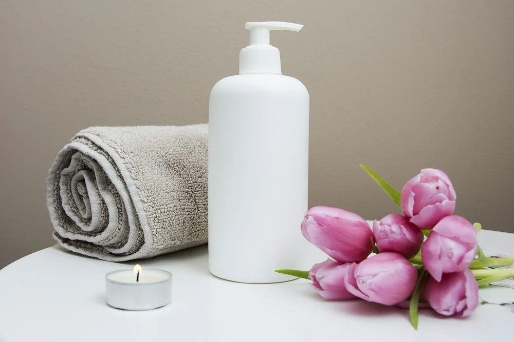 Produtos de cuidado, toalha e flores no exemplo Essenza Estética